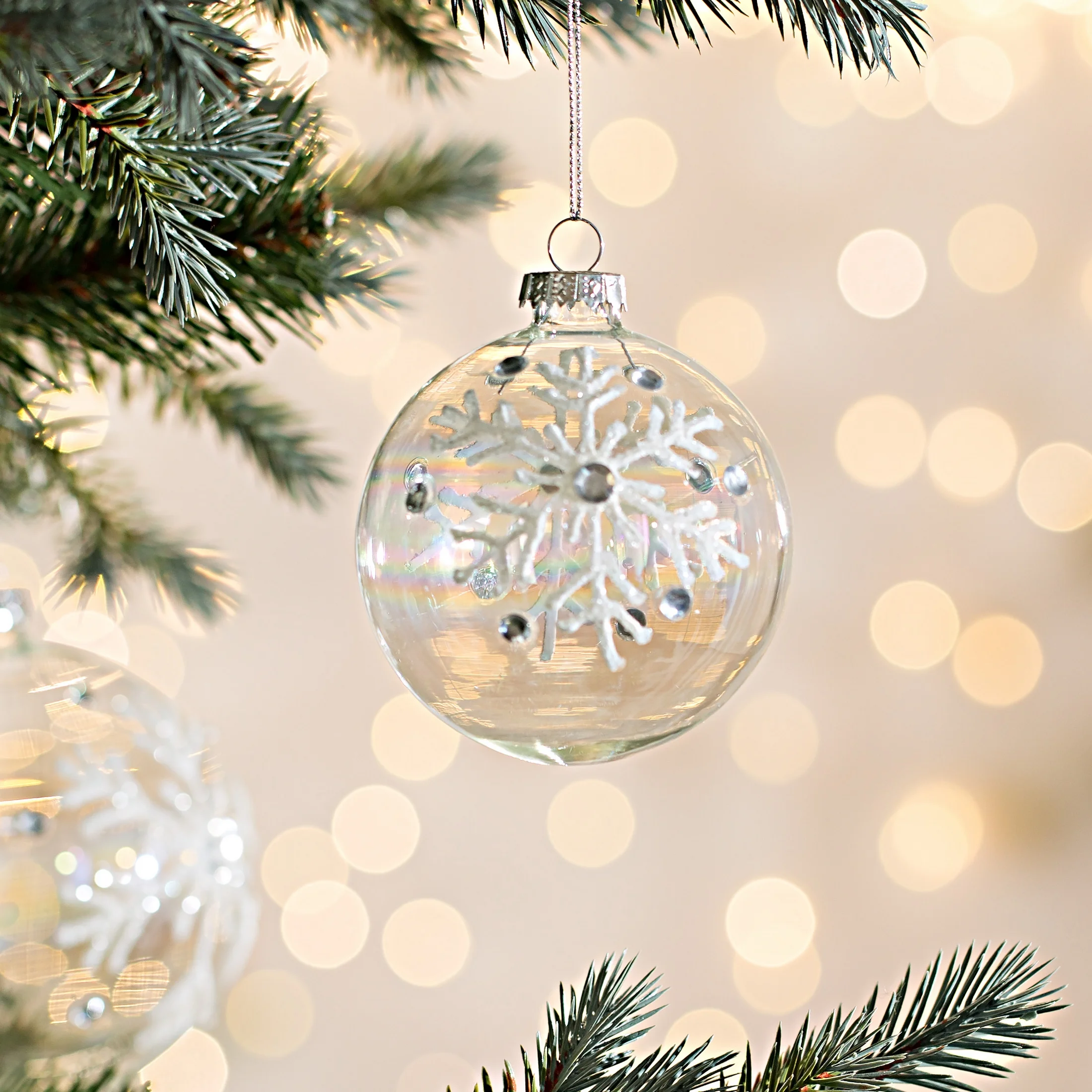 Bombka z transparentnego tęczowego szkła zdobiona śnieżynkami z brokatu oraz kryształkami | eurofirany