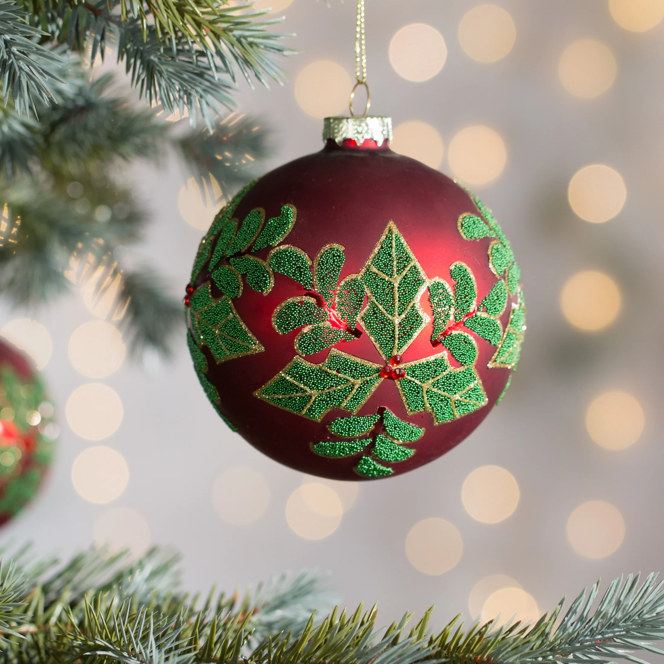 Szklana bombka choinkowa ręcznie zdobiona błyszczącym wzorem ostrokrzewu |