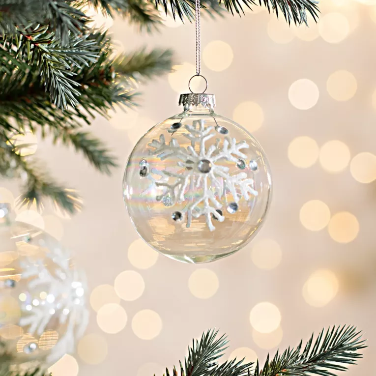 Bombka z transparentnego tęczowego szkła zdobiona śnieżynkami z brokatu oraz kryształkami