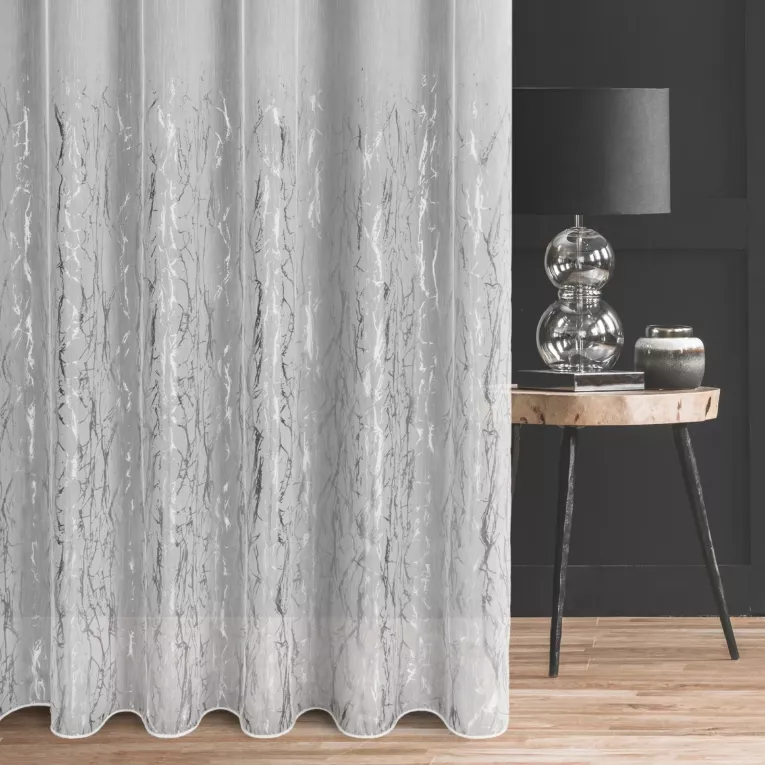 Firana szyta na taśmie 5 cm biało srebrzysta z tkaniny typu ADEN z efektem deszczyku, zdobionej niereguralnym srebrnym nadrukiem, wykończona obciążnikiem