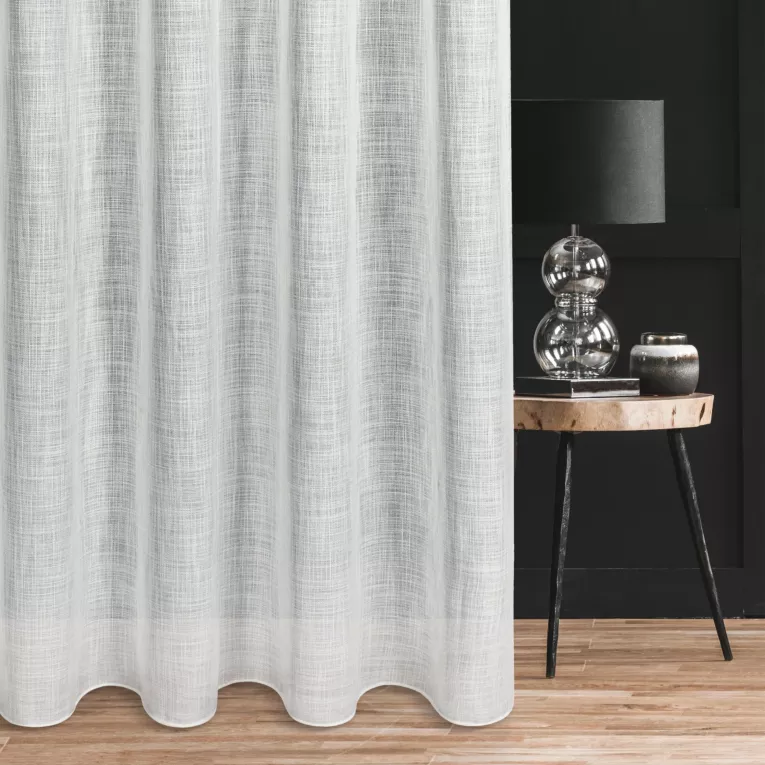 Firana szyta na taśmie 5 cm naturalna o luźnym splocie z dodatkiem transparentnej nici, nadającej delikatny połysk tkaninie, wykończona obciążnikiem