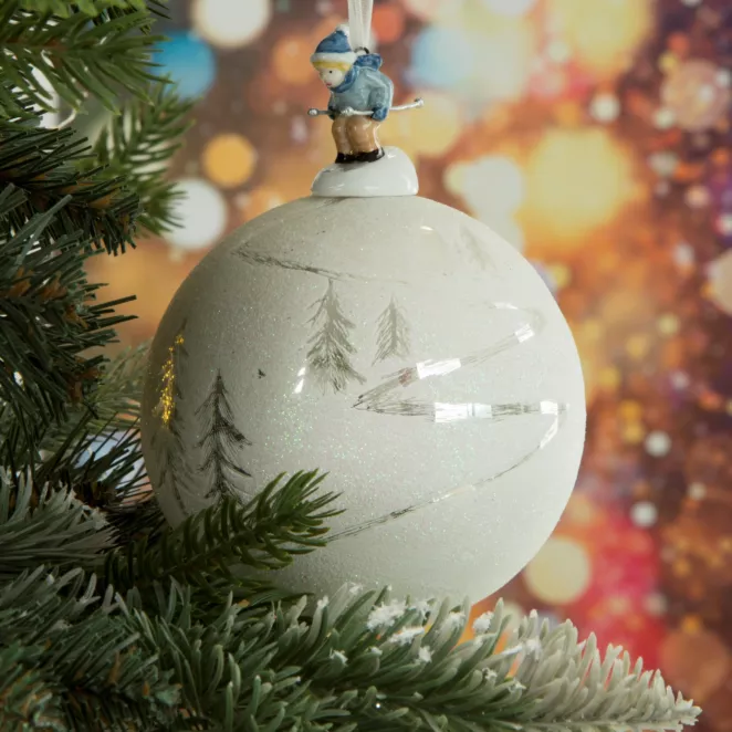 Bombka szklana zwieńczona szklaną figurką chłopczyka na nartach