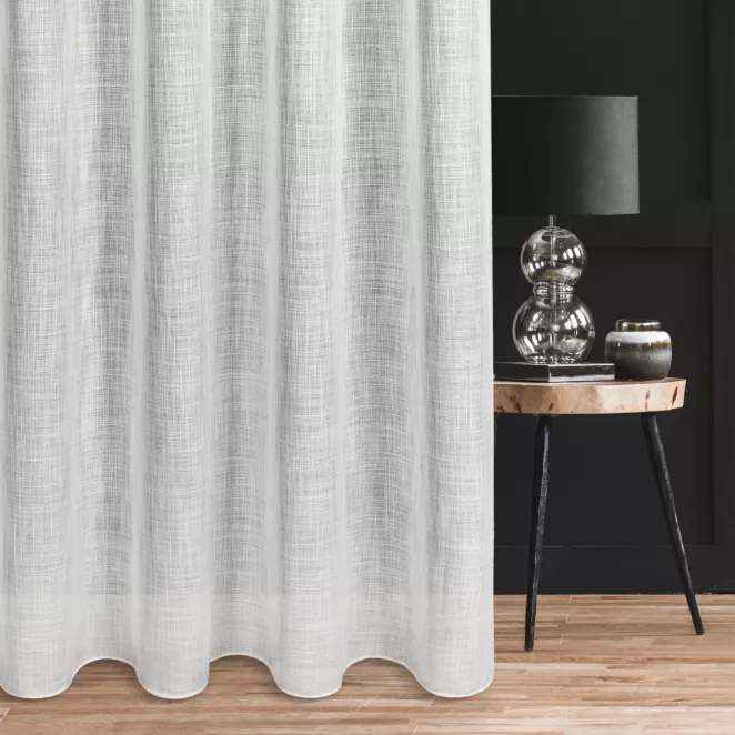 Firana szyta na taśmie 5 cm naturalna o luźnym splocie z dodatkiem transparentnej nici, nadającej delikatny połysk tkaninie, wykończona obciążnikiem