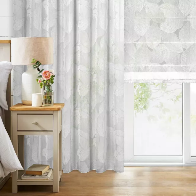 Roleta rzymska biało srebrna z tkaniny typu BATYST z delikatnie połyskującym nadrukiem w kształcie liści po całości tkaniny, wykończona obciążnikiem