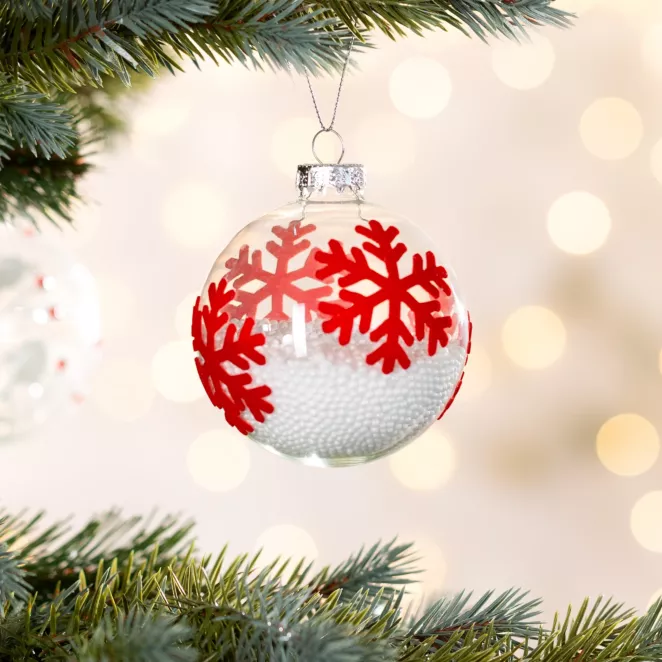 Bombka z transparentnego szkła z motywem czerwonych śnieżynek wypełniona sztucznym śniegiem