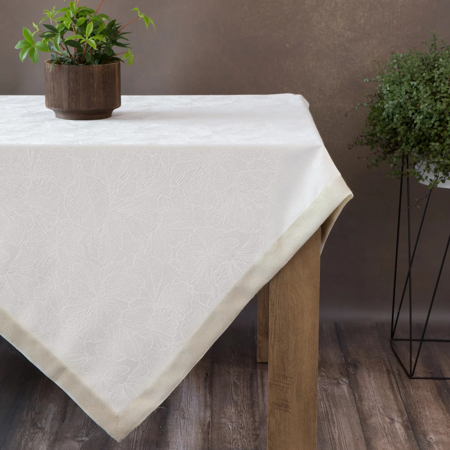 Obrus kremowy 145x400 cm LILIAN z delikatnym wzorem liści z tkaniny przeplatanej złotą nicią z elegancką podwójną listwą